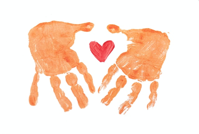 orange hand prints made from paint and a red painted heart in-between